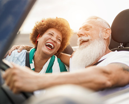 happy senior couple driving in convertible