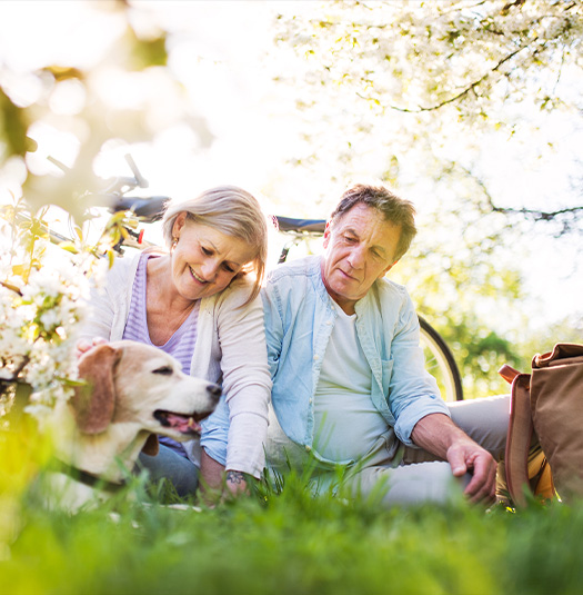 senior couple sitting in the grass with their dog annuity for retirement